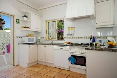 a kitchen with white cabinets and a stove top oven at Villa Primavera by Villa Plus in Albufeira