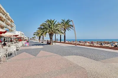 a street with chairs and palm trees and the beach at Quarteira Beach & Ocean View by Homing in Quarteira