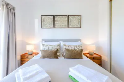 a bedroom with a white bed with two night stands at Casa Europa in Vilamoura