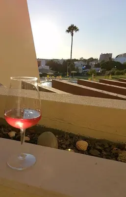a glass of wine sitting on a table near a pool at Apartamento T2 Palmeira Galé-Praia da Galé in Guia