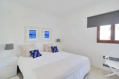 a white bedroom with a large white bed with blue pillows at Apt 1 Quarto, Piscina, AC, Varanda, Prestige For Home in Vilamoura