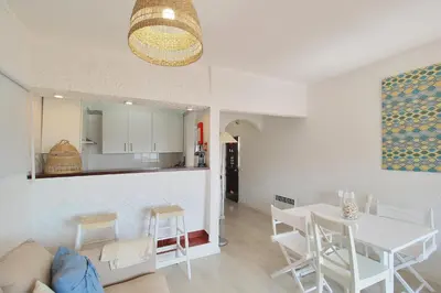 a living room and kitchen with a white table and chairs at Apt 1 Quarto, Piscina, AC, Varanda, Prestige For Home in Vilamoura