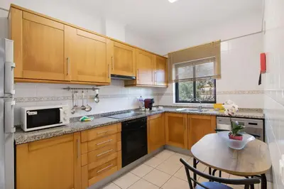 a kitchen with wooden cabinets and a small table at T1 Apartamentos Vista Alegre in Albufeira