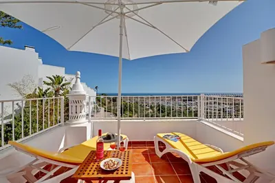 a balcony with a table and chairs and an umbrella at Casa Roos Loïs in Albufeira