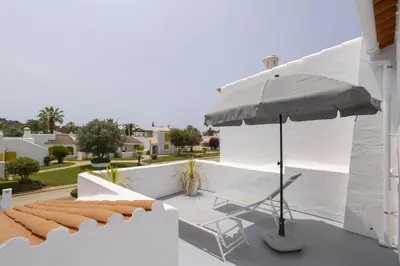 a patio with an umbrella and a chair at Hopstays Vilamoura Aldeia do Golfe - House C3 in Vilamoura