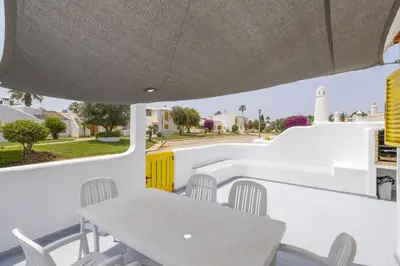 a table and chairs on a patio with a view of a street at Hopstays Vilamoura Aldeia do Golfe - House C3 in Vilamoura