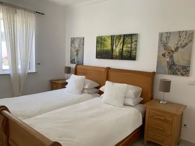 a bedroom with two beds and two lamps and a window at Villa Karon in Almancil