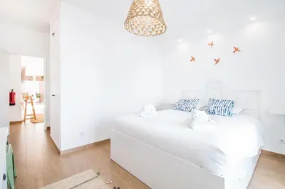 a white bedroom with a white bed with blue pillows at Bambu Villa in Albufeira