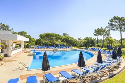 a swimming pool with chairs and umbrellas at Quinta do Lago - Beach,Ténis, Bikes in Quinta do Lago