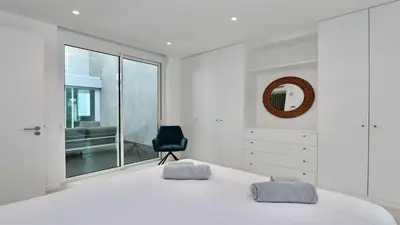 a bedroom with a white bed and a black chair at Villa Terese-CleverDetails, Central Vilamoura, Sleeps 6, luxury, walking distance in Vilamoura
