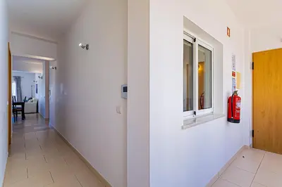 a hallway with a fire extinguisher on the wall at Frente praia SIM T3 Praia Quarteira by HsRentals in Quarteira