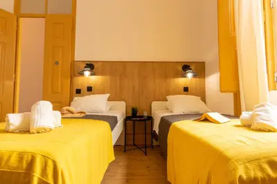 a hotel room with two beds with yellow sheets at GrowIN Digital Nomads in Faro
