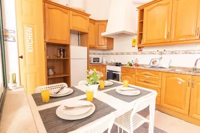 a kitchen with wooden cabinets and a white table and chairs at GrowIN Digital Nomads in Faro