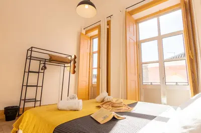 a bedroom with a bed with a yellow bedspread and a window at GrowIN Digital Nomads in Faro