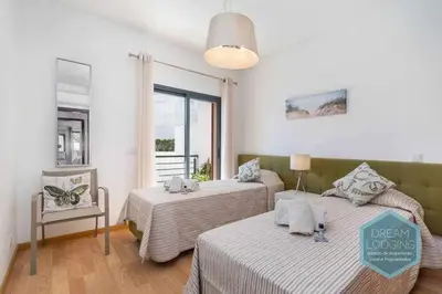 a bedroom with two beds and a chair and a window at Terrace Miguel Torga - Dream Lodging in Albufeira