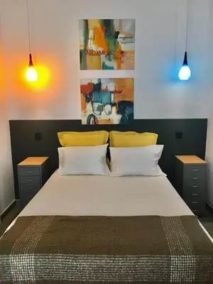 a bedroom with a large bed with two yellow pillows at Casa dos Retratos Faro in Faro