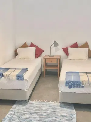 two beds in a room with a table and a lamp at Casa dos Retratos Faro in Faro