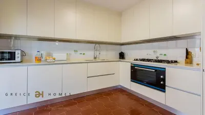 a kitchen with white cabinets and a stove top oven at Greice Homes-650 meters from the beach, 4 bedrooms villa for holidays in Vilamoura-Quarteira in Quarteira
