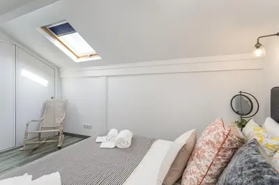 a bedroom with a bed and a chair at Casa Lobo - 2 bedrooms - Duplex in Faro