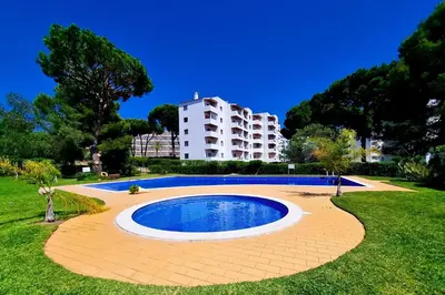 a swimming pool in a park with a building in the background at FLH Vilamoura Balcony with Pool in Vilamoura