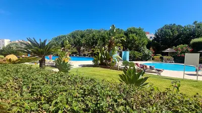 a resort with a swimming pool with people laying in the grass at 2 Terrace Town House in Albufeira