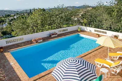 a swimming pool with an umbrella and two umbrellas at Charming House with Pool in Faro in Faro