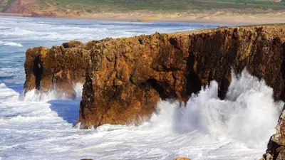 a large cliff in the ocean with water crashing onto it at Charming House with Pool in Faro in Faro