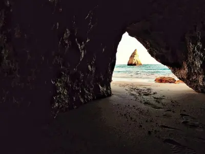 a cave entrance to a beach with a rock in the ocean at Charming House with Pool in Faro in Faro