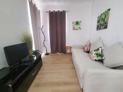 a living room with a white couch and a television at Sun Apartment on the Beach in Albufeira
