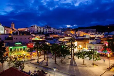 a city at night with palm trees and buildings at Sun Apartment on the Beach in Albufeira
