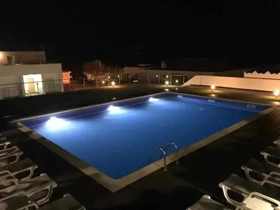 a large blue swimming pool with chairs at night at Villa Amazing View - S in Albufeira