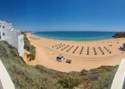 a beach with umbrellas and chairs and the ocean at Terrace apartament on the Sea in Albufeira