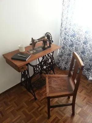 an old sewing machine sitting on a table with a chair at Lemon Tree Apartments in Faro