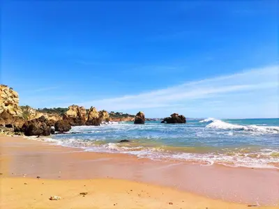 a sandy beach with rocks in the ocean at Beach Condo with Atlantic Ocean View by BeCherish in Olhos de Água