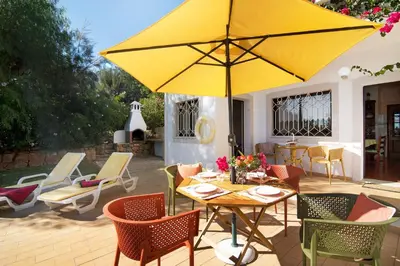 a patio with a table with a yellow umbrella at Casa da Alfarrobeira in Loulé
