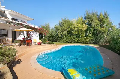a swimming pool with a chair and a house at Casa da Alfarrobeira in Loulé