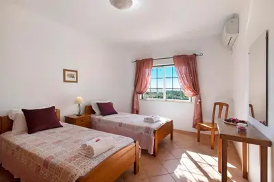 two beds in a small room with wooden cabinets at Casa do Barrocal in Almancil