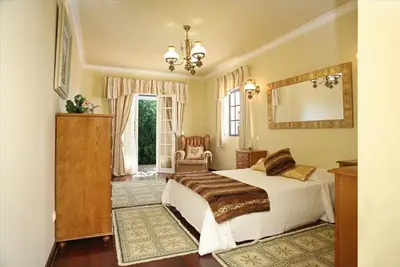 a bedroom with a bed and a mirror and a chair at Villa Jumar in Albufeira