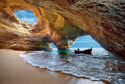 a boat in the water under a rock cave at AlbufeiraSun, arrive as a guest leave as a friend. in Albufeira