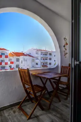 a table and chairs on a balcony with a view of buildings at AlbufeiraSun, arrive as a guest leave as a friend. in Albufeira