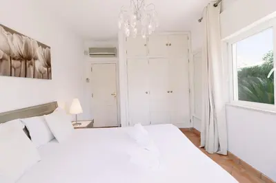 a white bedroom with a white bed and a window at Villa Sara in Quarteira