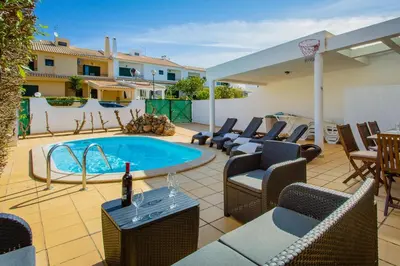 a patio with chairs and a pool with a basketball hoop at Sunny 2BDR House W/ Private Pool by LovelyStay in Albufeira