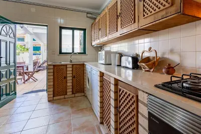 a kitchen with wooden cabinets and a counter top at Sunny 2BDR House W/ Private Pool by LovelyStay in Albufeira