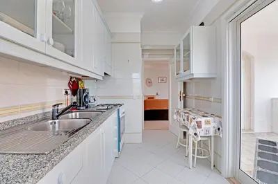a kitchen with white cabinets and a sink at Vilamoura Main Avenue by Homing in Vilamoura