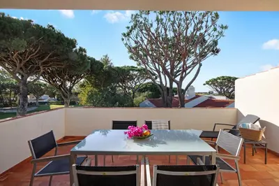 a table and chairs on a patio with trees at Casa Las Trinitarias in Vale do Lobo