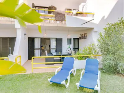 a patio with two blue chairs and a table at AL - Apartamento Sunrise, Sol Nascente 1 Ground floor in Vilamoura