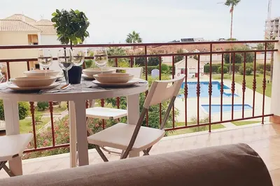 a table with chairs and wine glasses on a balcony at Lindo apartamento junto à praia e à Marina de Vilamoura com Piscina e Wi-Fi in Quarteira