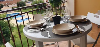 a table with plates and wine glasses on a balcony at Lindo apartamento junto à praia e à Marina de Vilamoura com Piscina e Wi-Fi in Quarteira