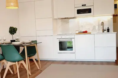 a kitchen with white cabinets and a table and chairs at Lindo apartamento junto à praia e à Marina de Vilamoura com Piscina e Wi-Fi in Quarteira