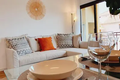 a living room with a couch and a table with wine glasses at Lindo apartamento junto à praia e à Marina de Vilamoura com Piscina e Wi-Fi in Quarteira